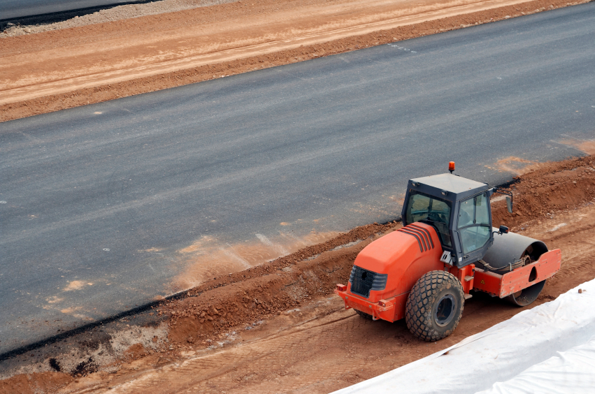 Heavy equipment compacting soil to underlay a new road